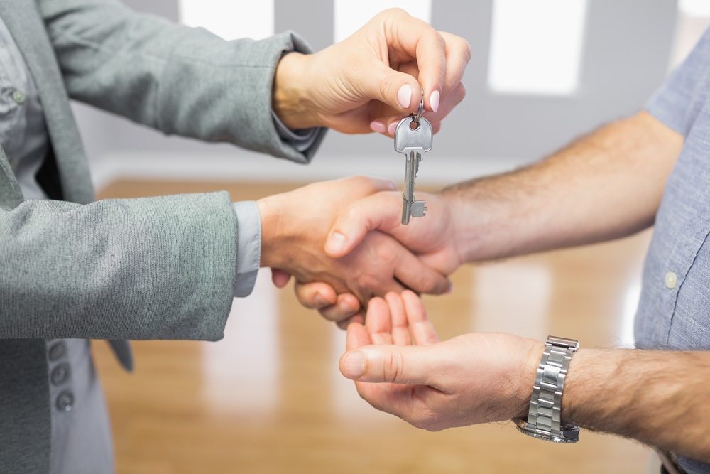 Close up of a man receiving a handshake and a key at the same time